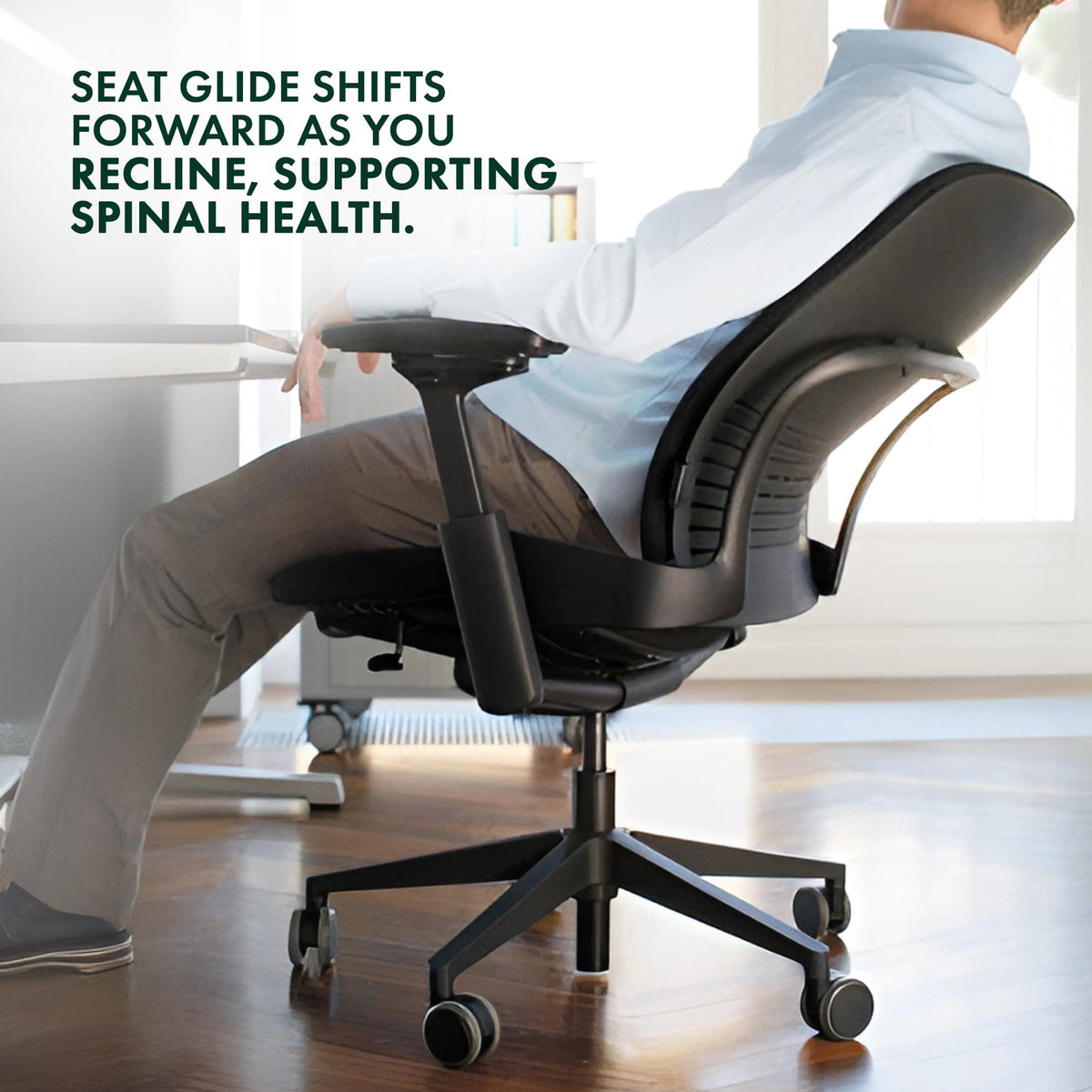 Man reclining in a renewed Steelcase Leap V2 office chair with black base at a desk